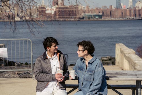 Free Young female friends chatting on waterfront during coffee break Stock Photo