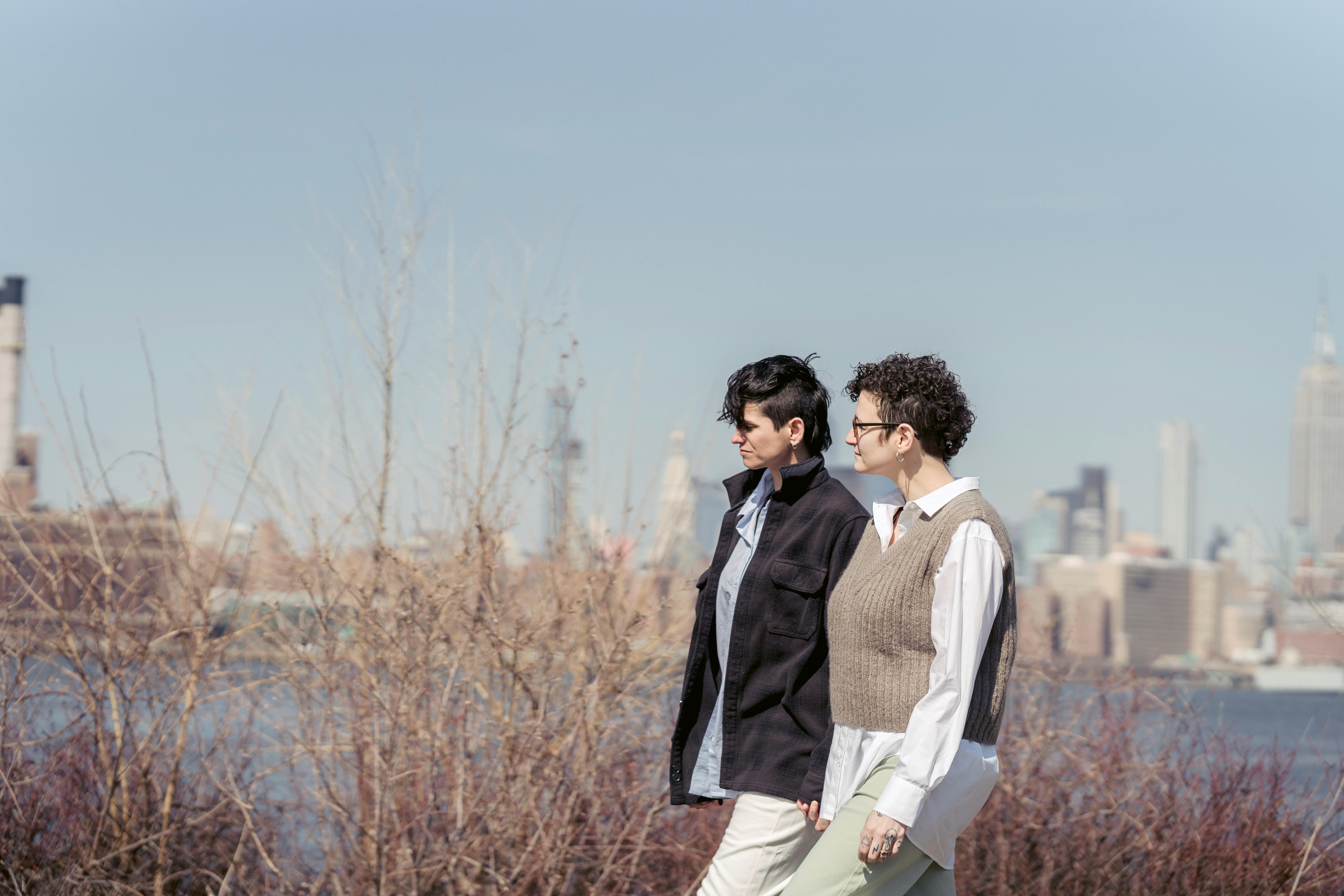 romantic lesbian couple holding hands and strolling on river bank