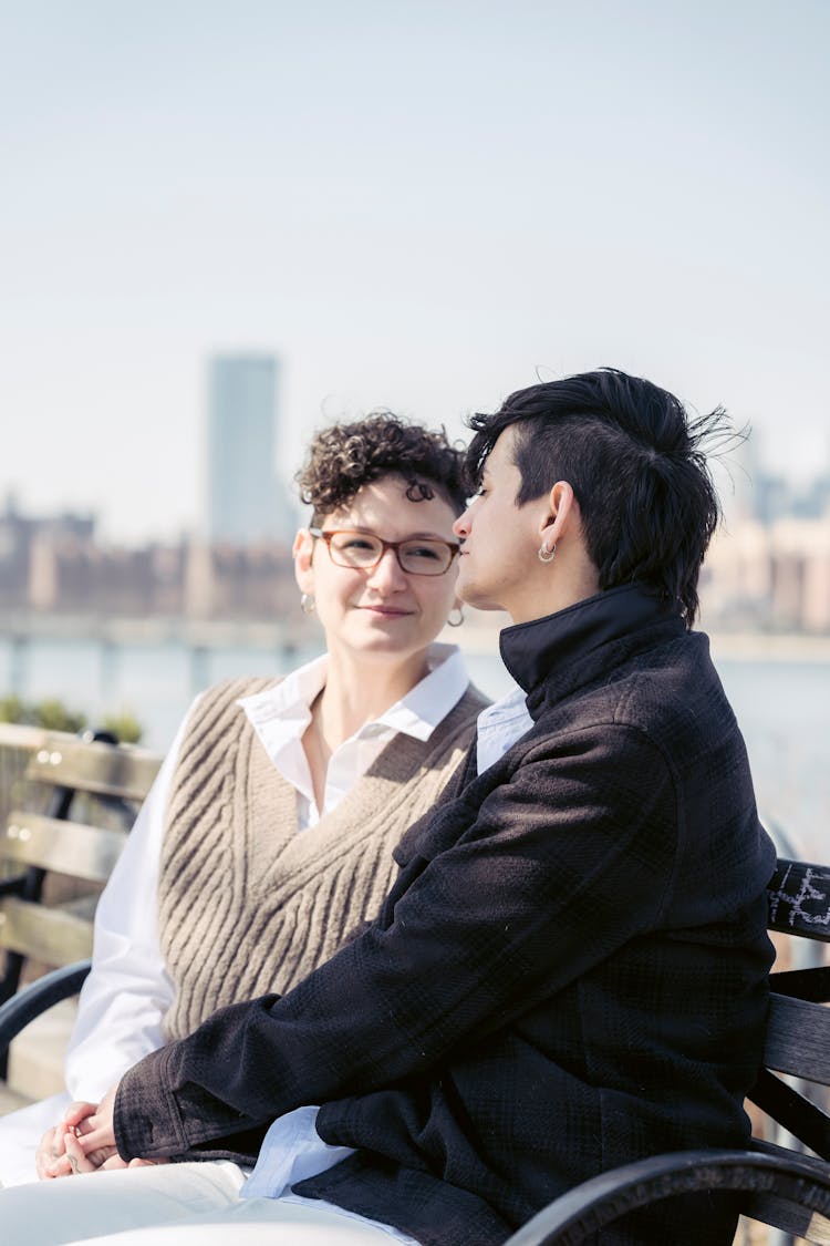 Positive Women Talking On Bench In Park