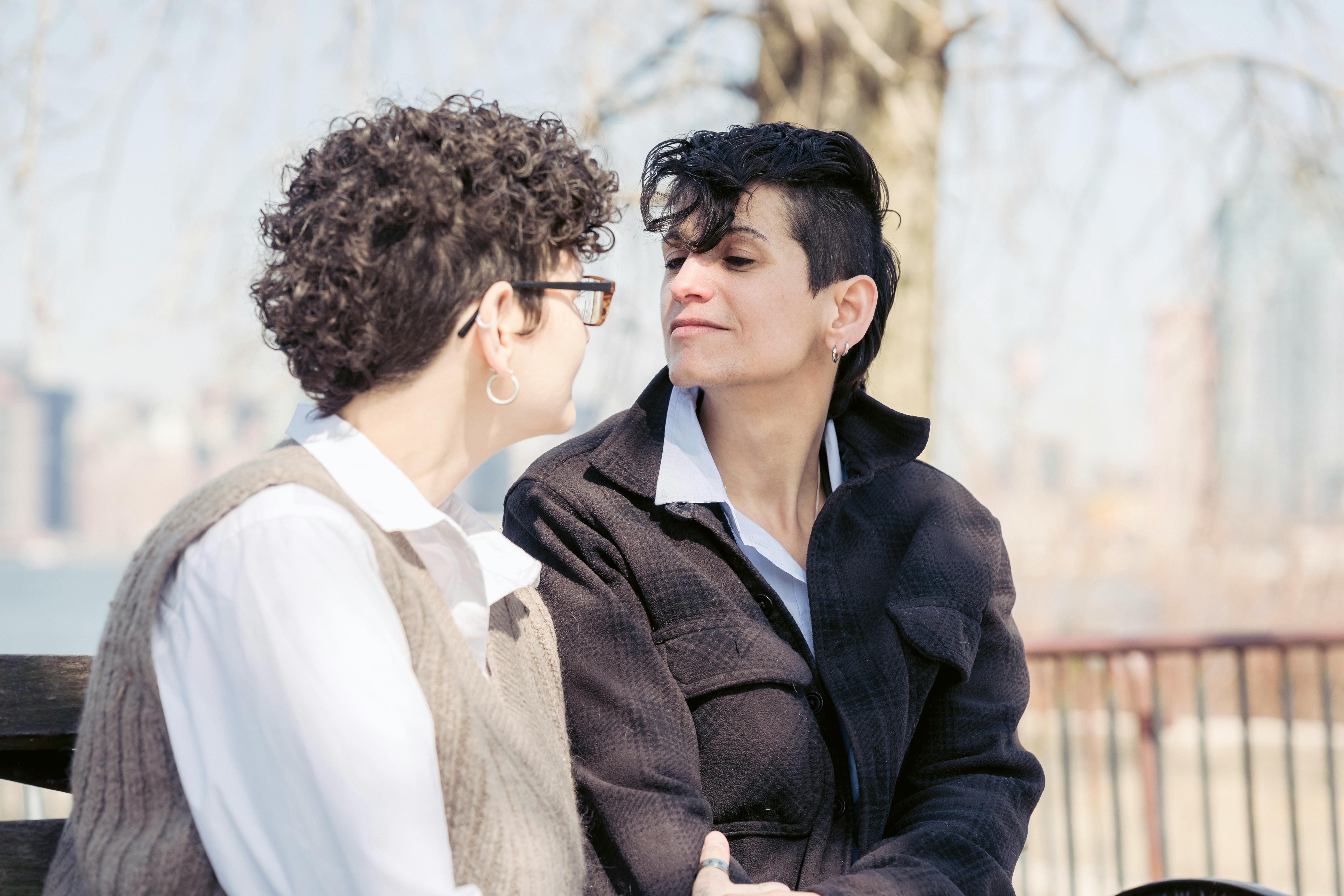 positive lesbian couple sitting on bench and looking at each other