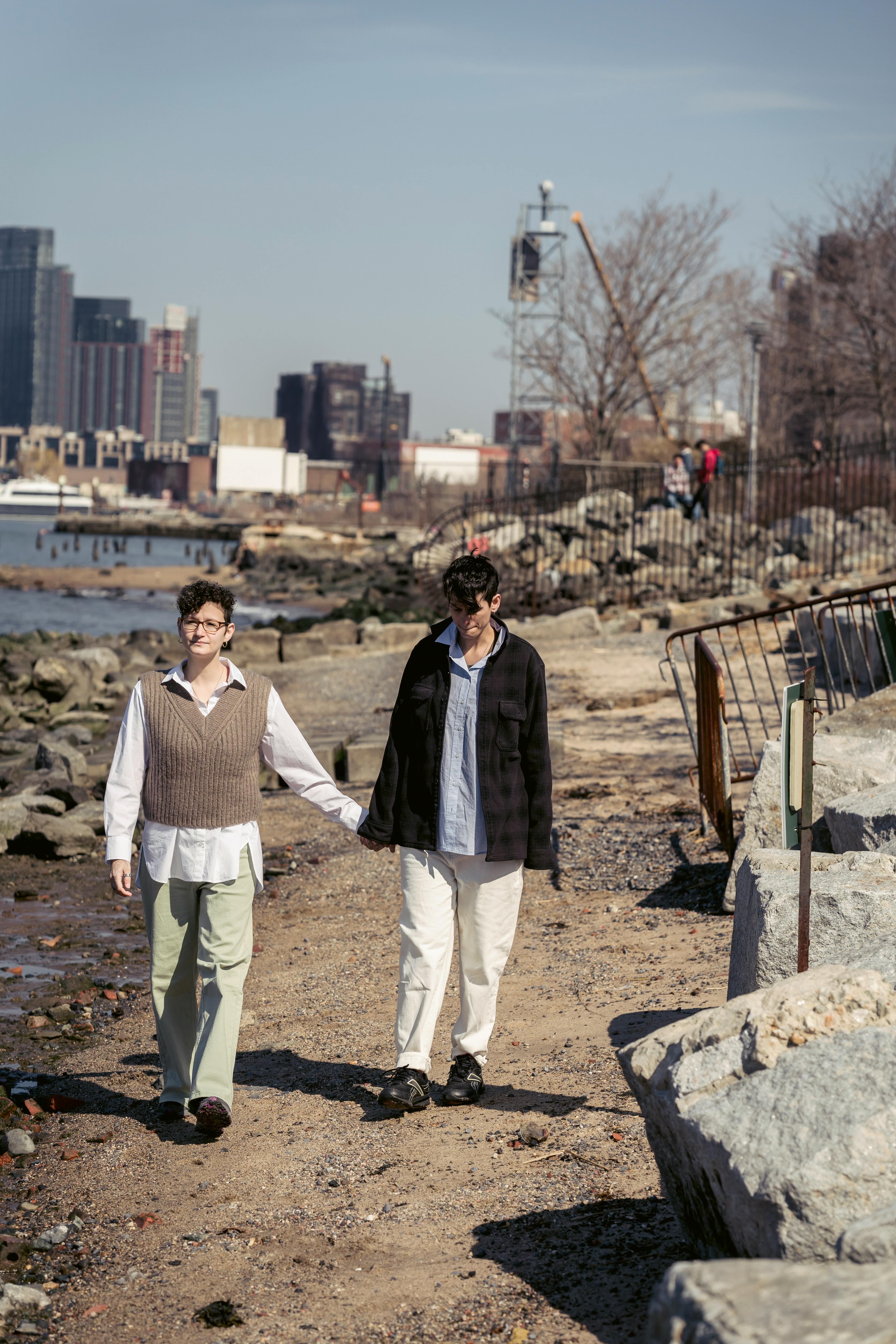 lesbian couple walking near river in city in sunny day