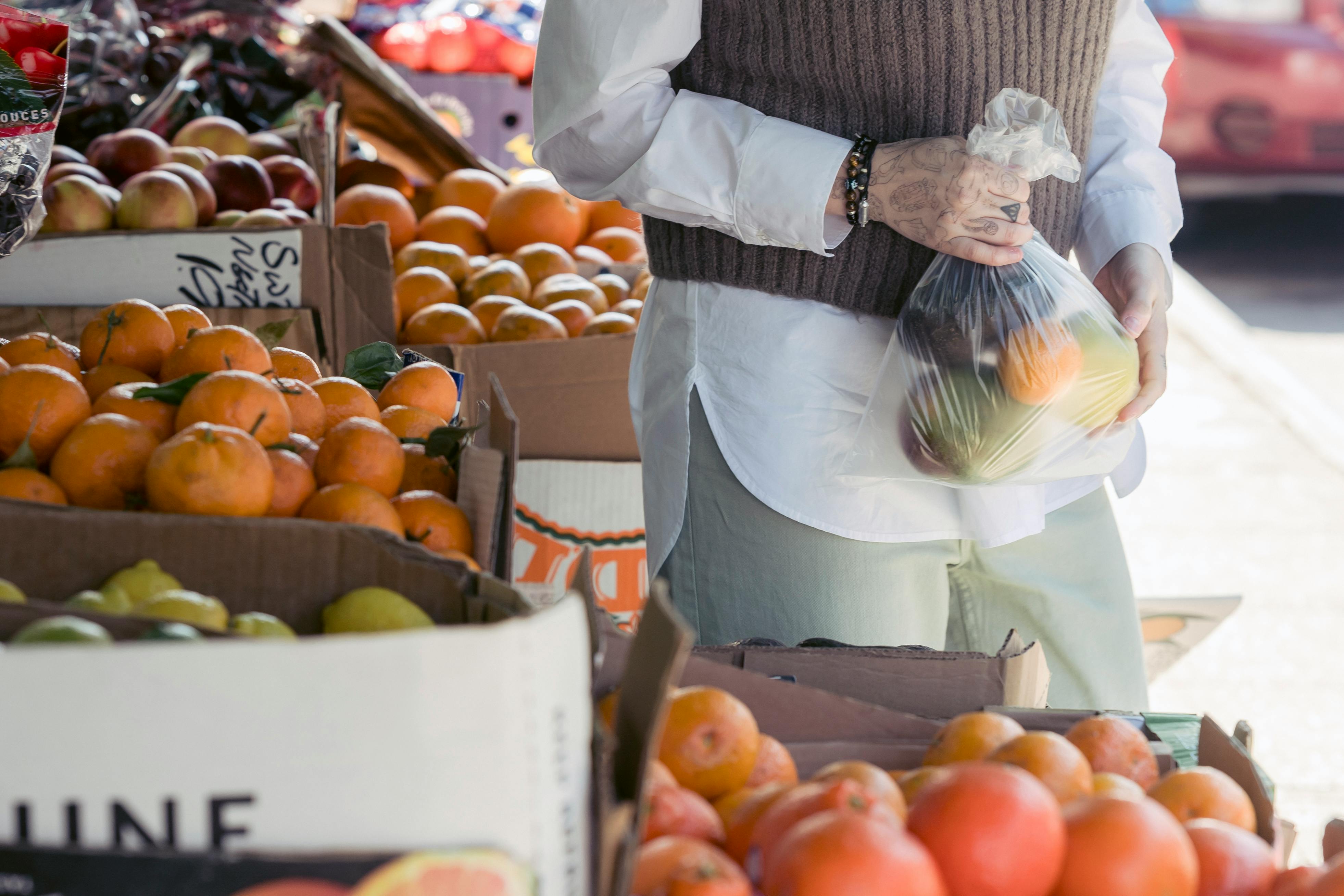 anonymous woman choosing citruses in grocery market in daylight