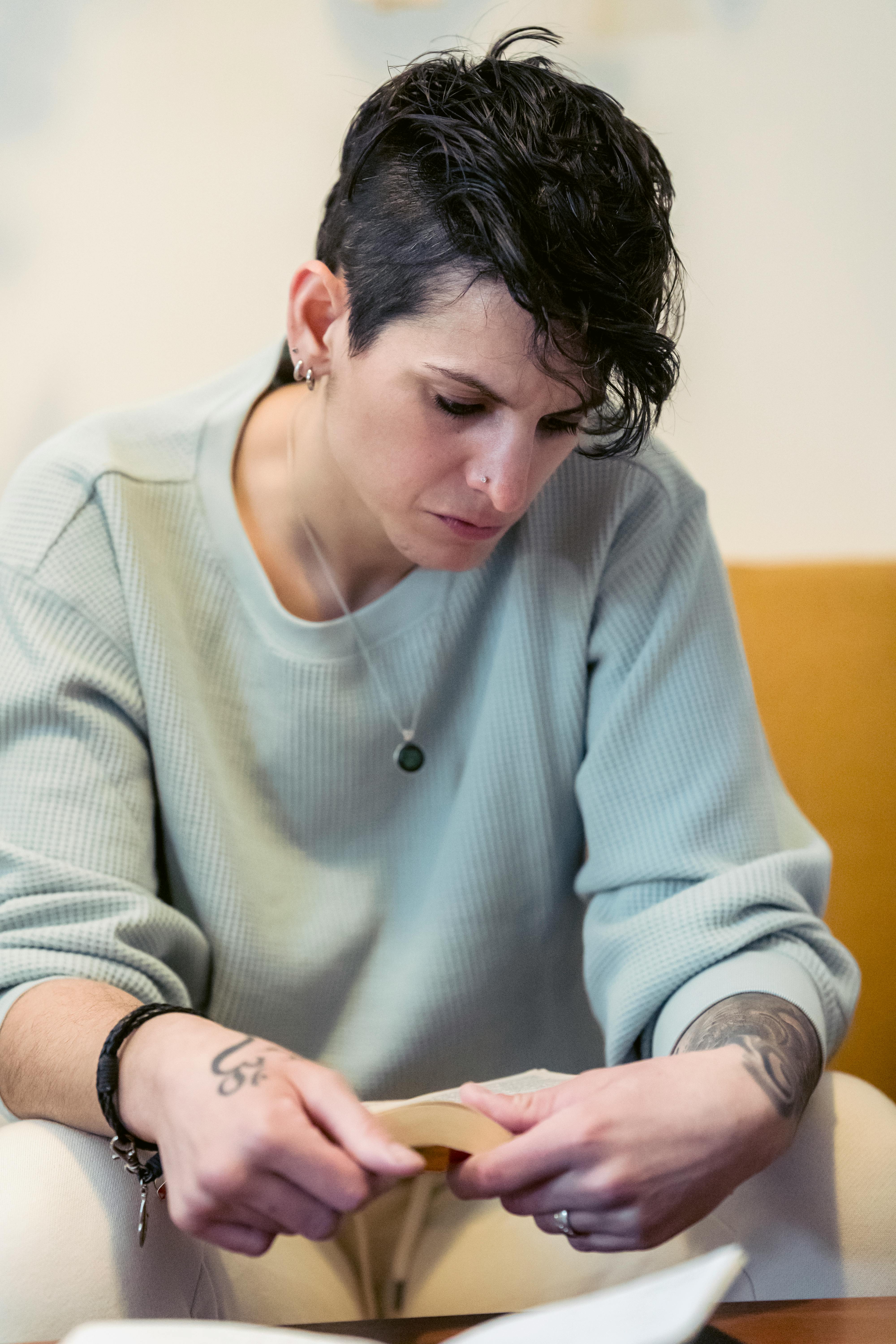 serious young informal woman reading book on sofa