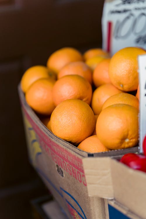 Box with heap of fresh oranges in street food market