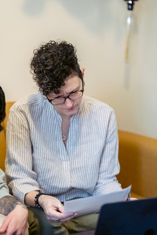 Serious young female entrepreneur reading contract near crop partner