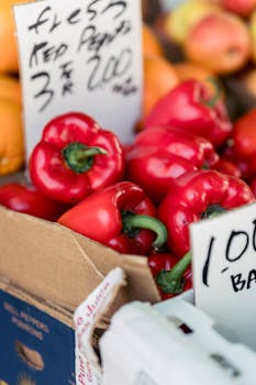 Vibrant fresh red bell peppers on display at an outdoor market stall, perfect for healthy cooking.