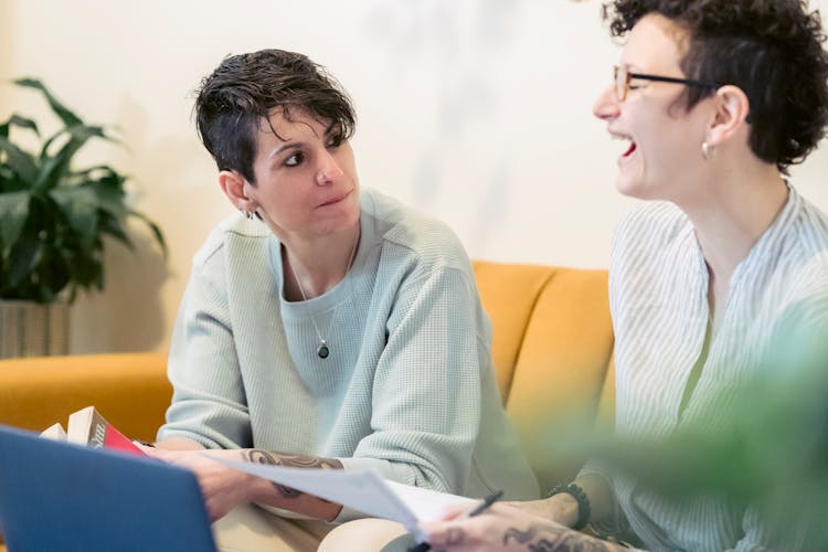 Joyful Young Woman Laughing While Chatting With Friend During Remote Work