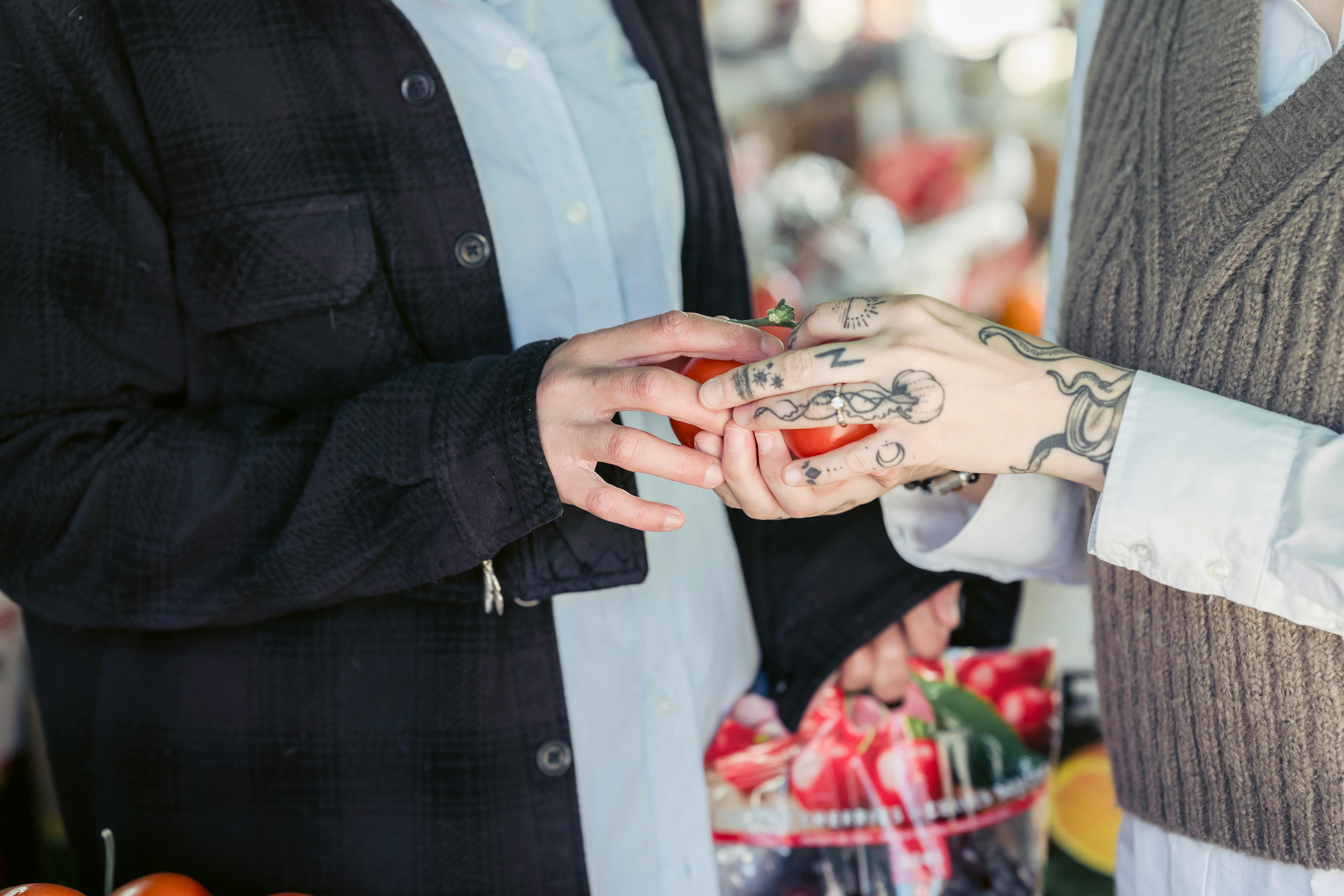 anonymous couple purchasing vegetables in market in sunlight