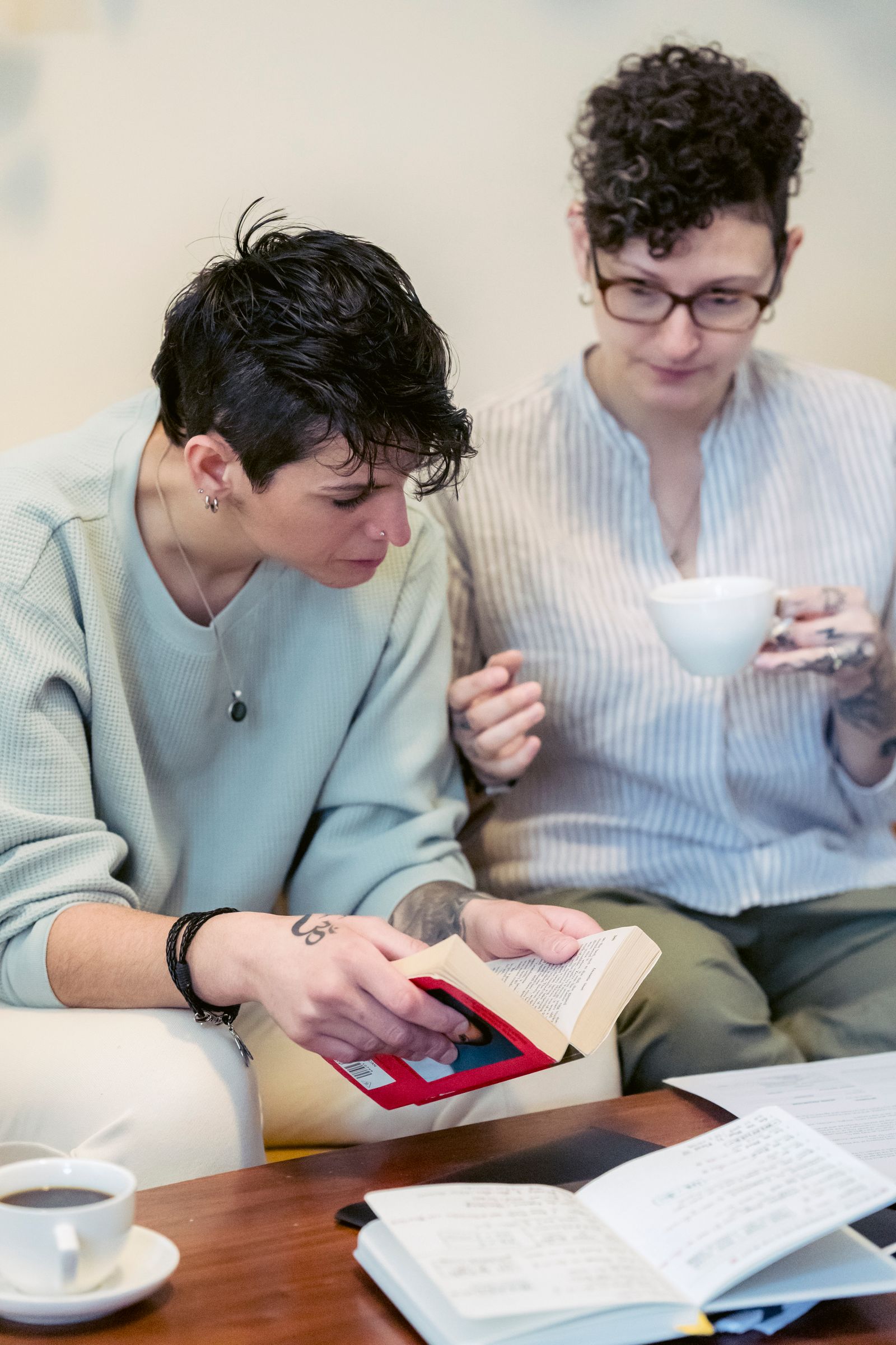 Two people talking with a book and coffee on a sofa