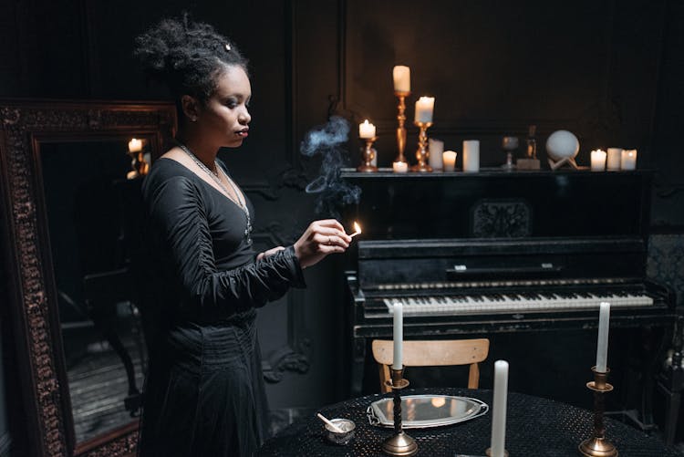 A Woman In Black Long Sleeve Dress Holding A Matchstick