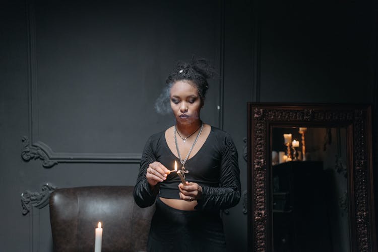 A Woman In Black Long Sleeve Crop Top Holding A Matchstick