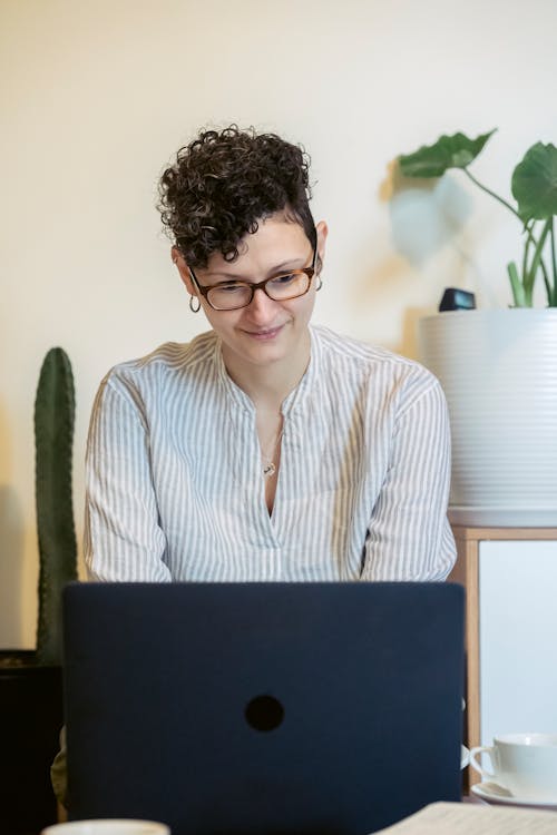 Free Smiling young female freelancer using laptop at home Stock Photo