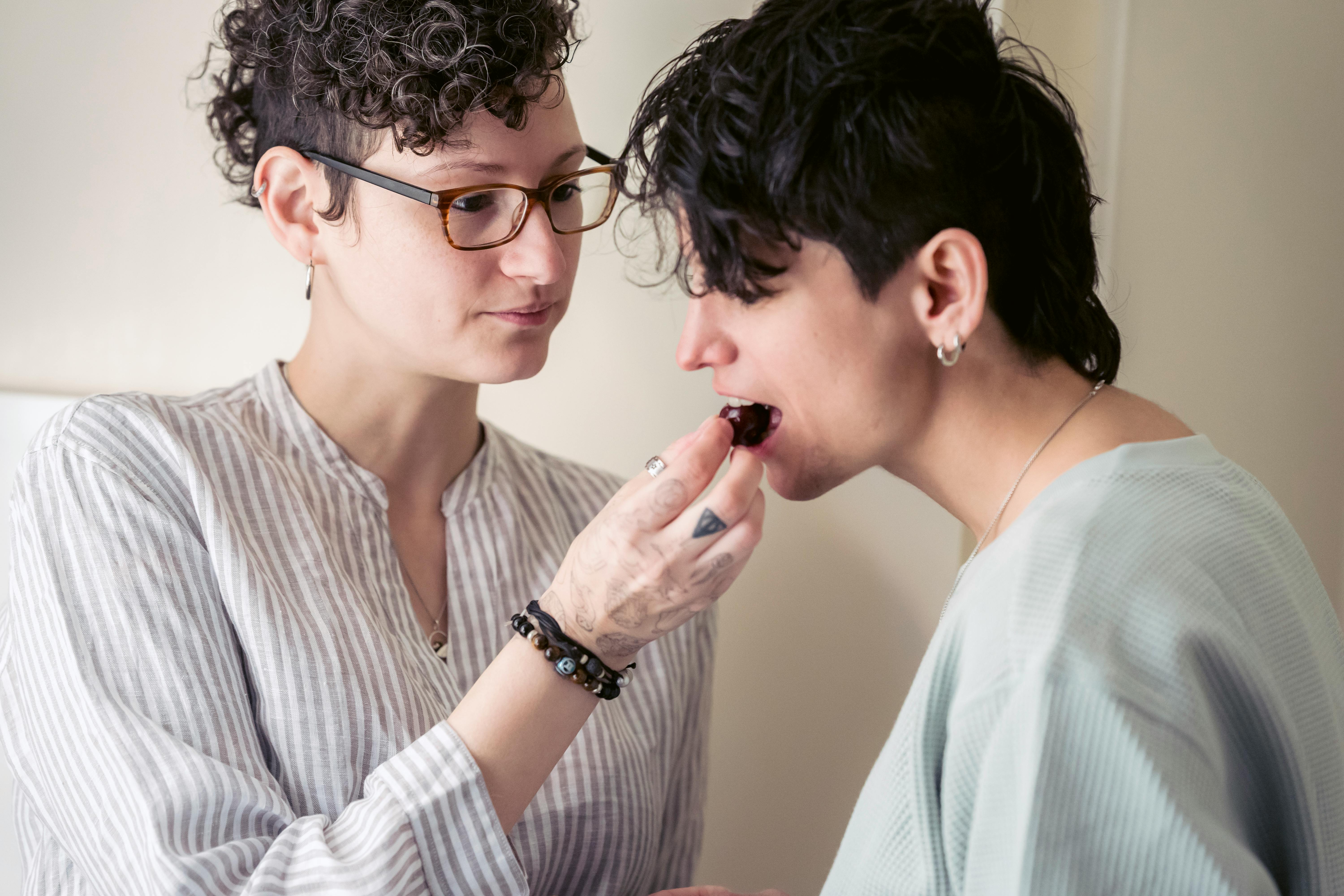 young woman feeding girlfriend with berry