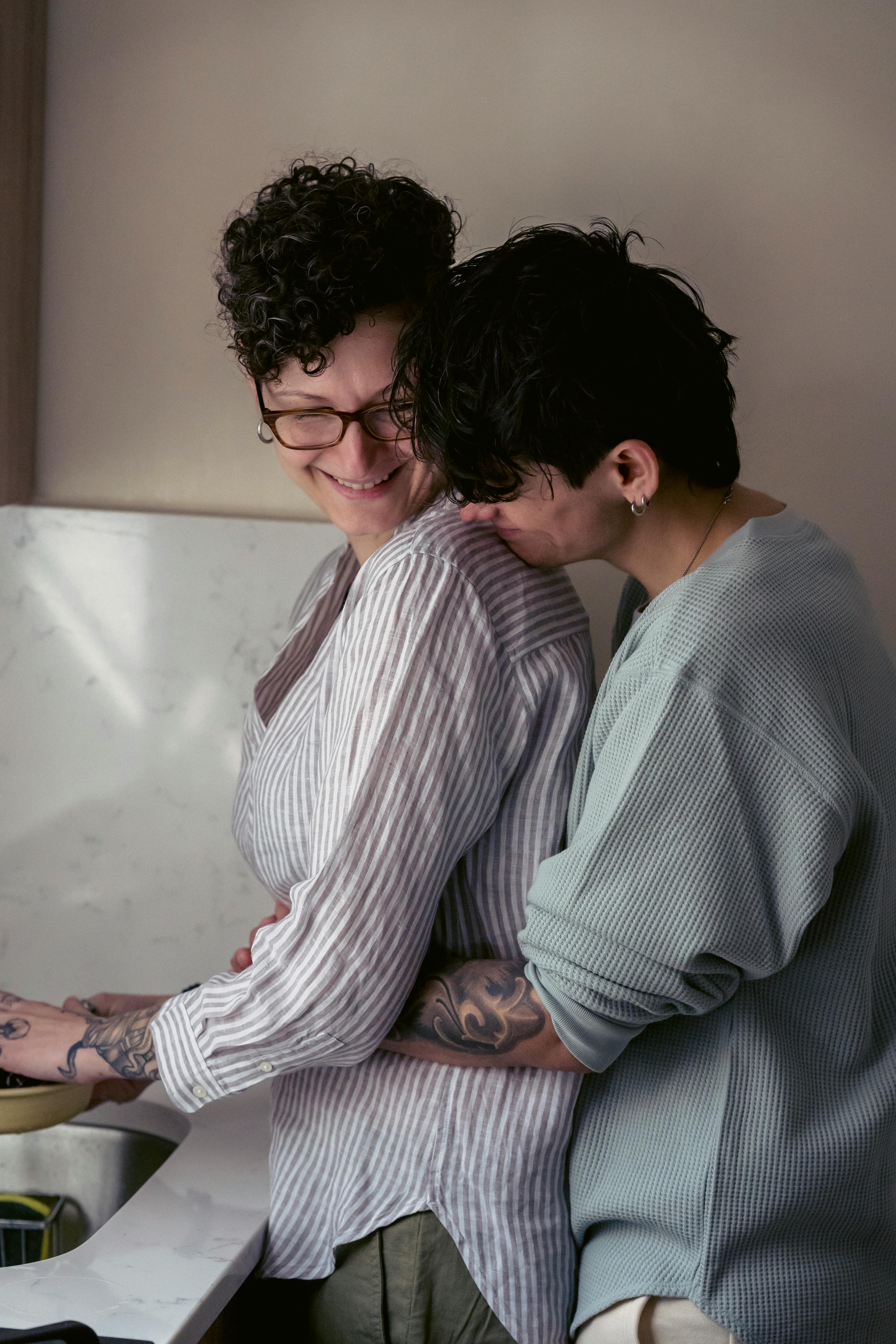 loving lesbians cuddling and smiling in kitchen