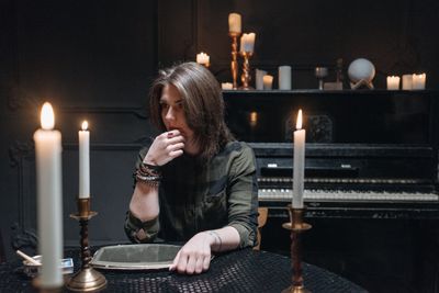 A woman sitting alone at a dark table lit by candles — Pavel Danilyuk on Pexels