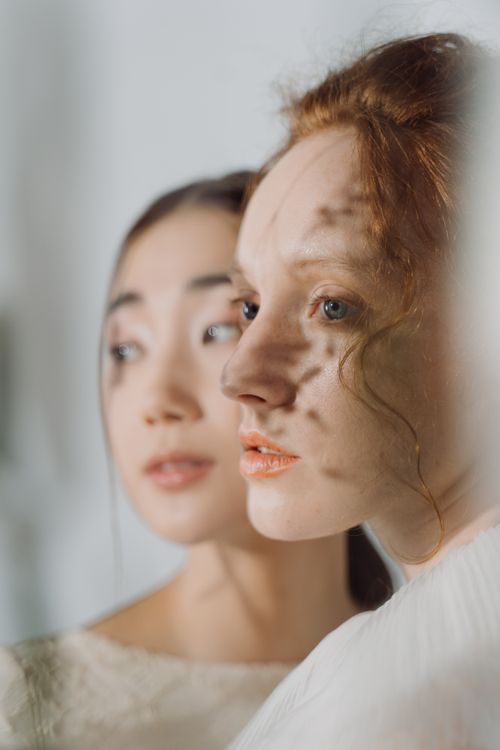 Free Close-up artistic portrait of two young women with soft focus and natural lighting in a studio setting. Stock Photo