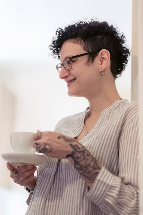 Smiling tattooed woman drinking coffee at home