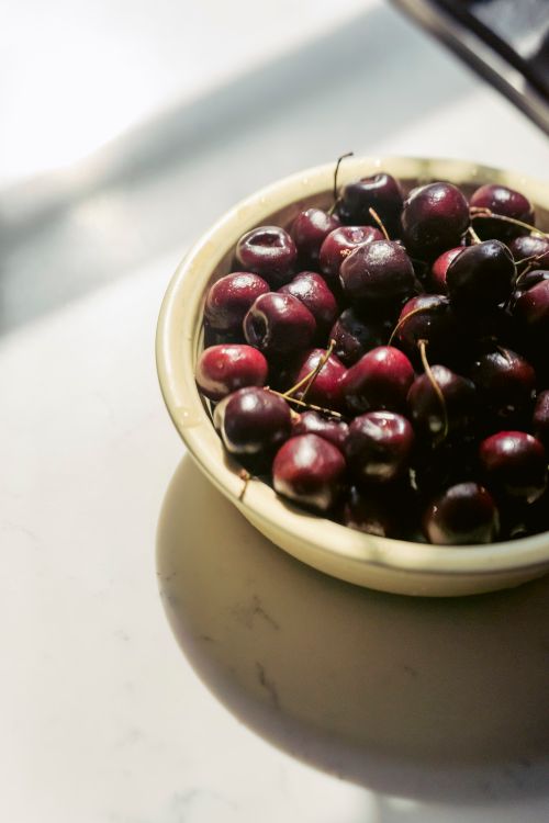 Free From above of heap of fresh ripe delicious cherries in bowl placed on table in sunlight Stock Photo