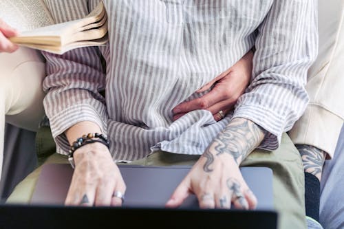 Free Crop couple with tattoos and laptop at home Stock Photo