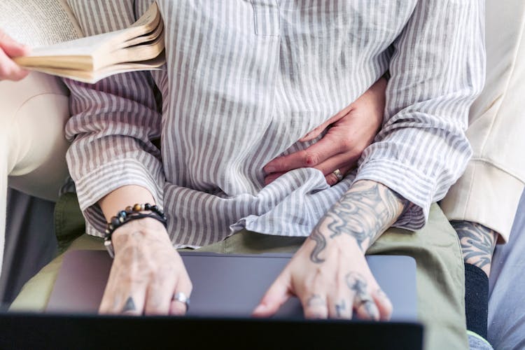 Crop Couple With Tattoos And Laptop At Home