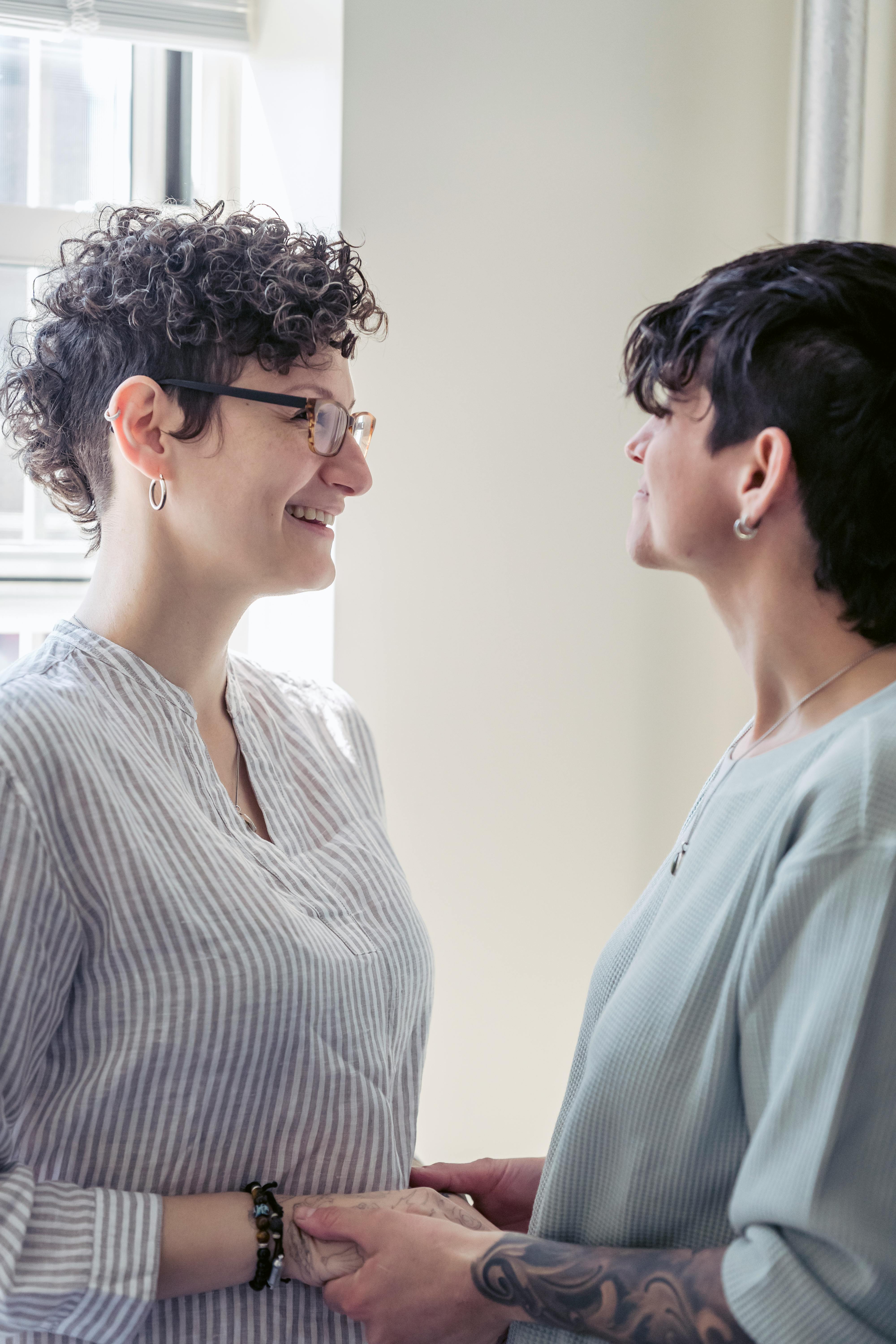 crop smiling lesbian couple talking at home