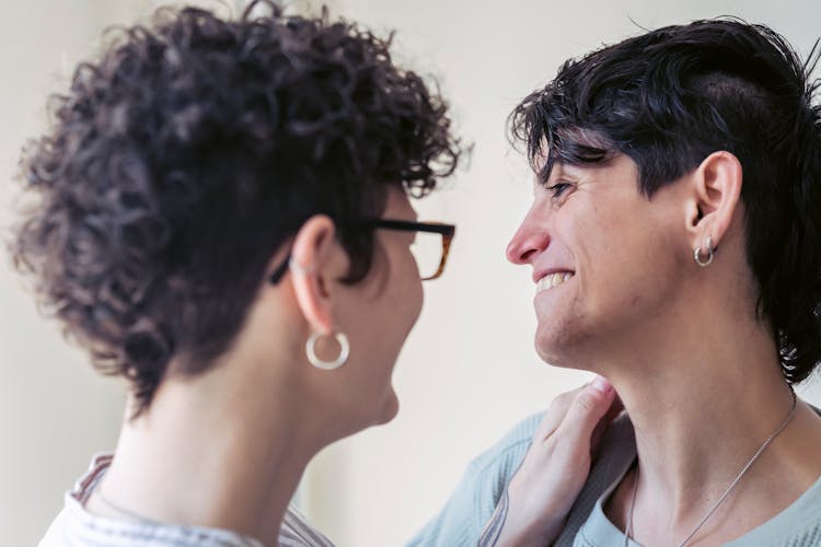 Smiling Homosexual Couple Embracing While Talking In House