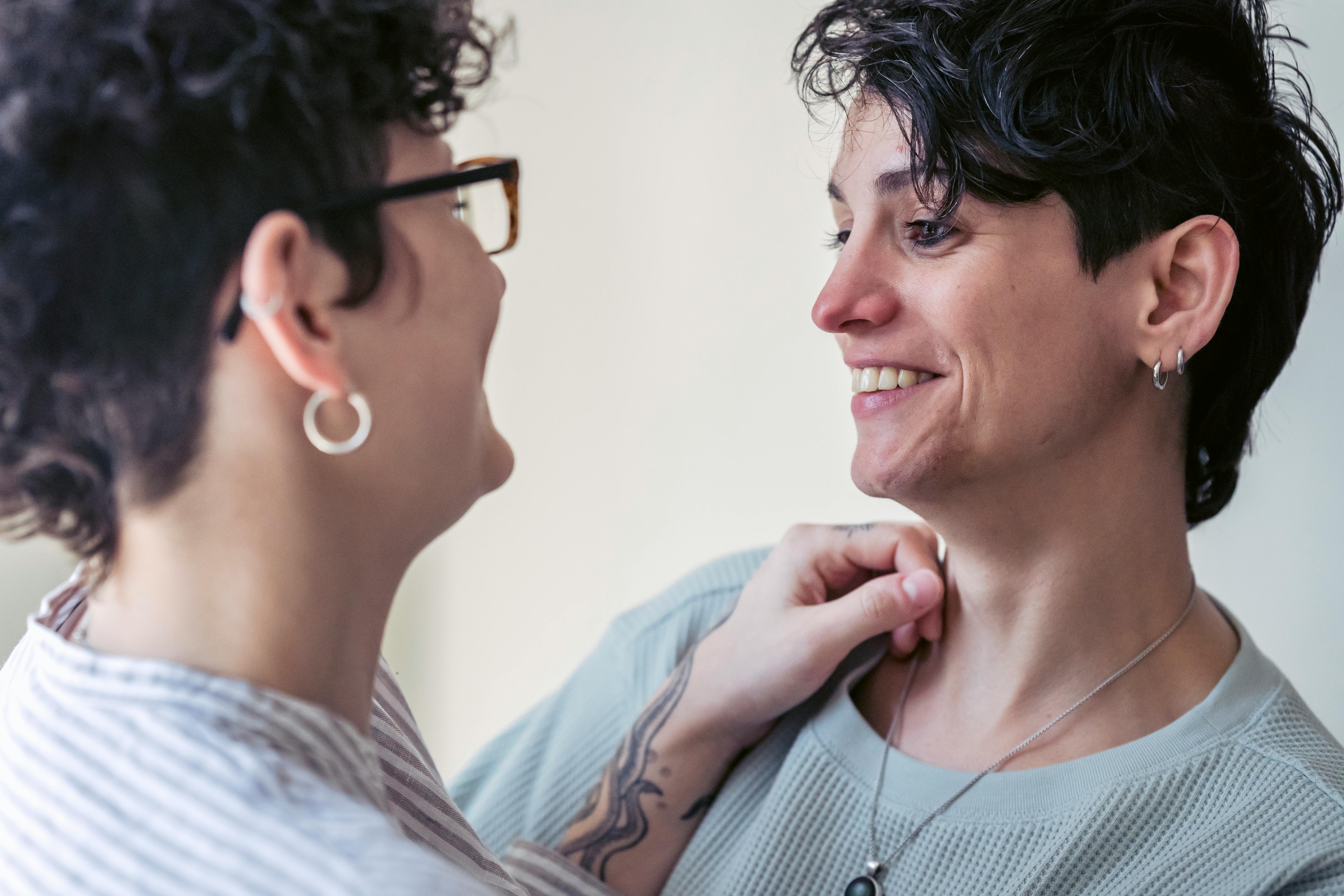 crop smiling lesbian couple embracing during conversation at home