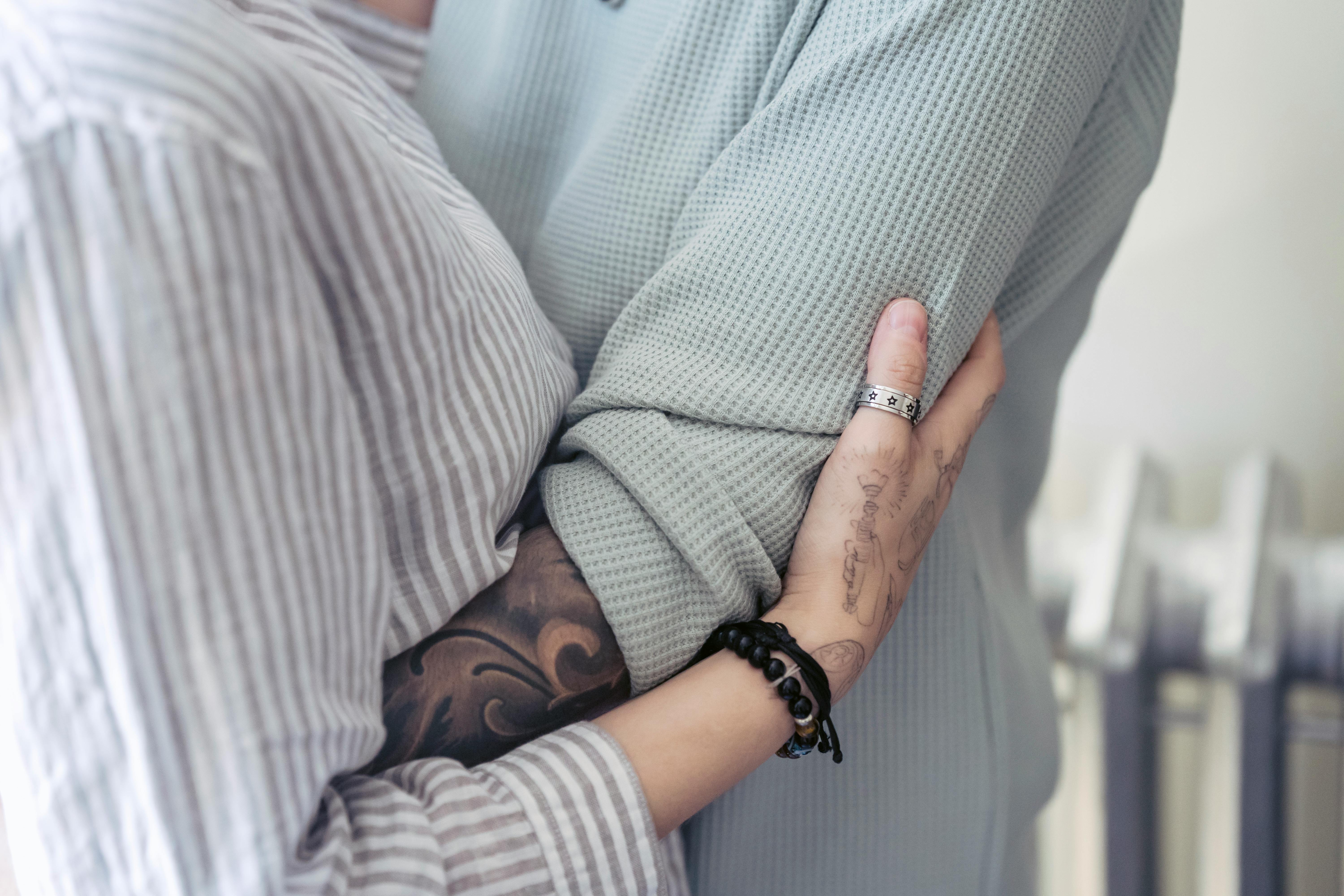 crop lesbian couple with tattoos embracing at home