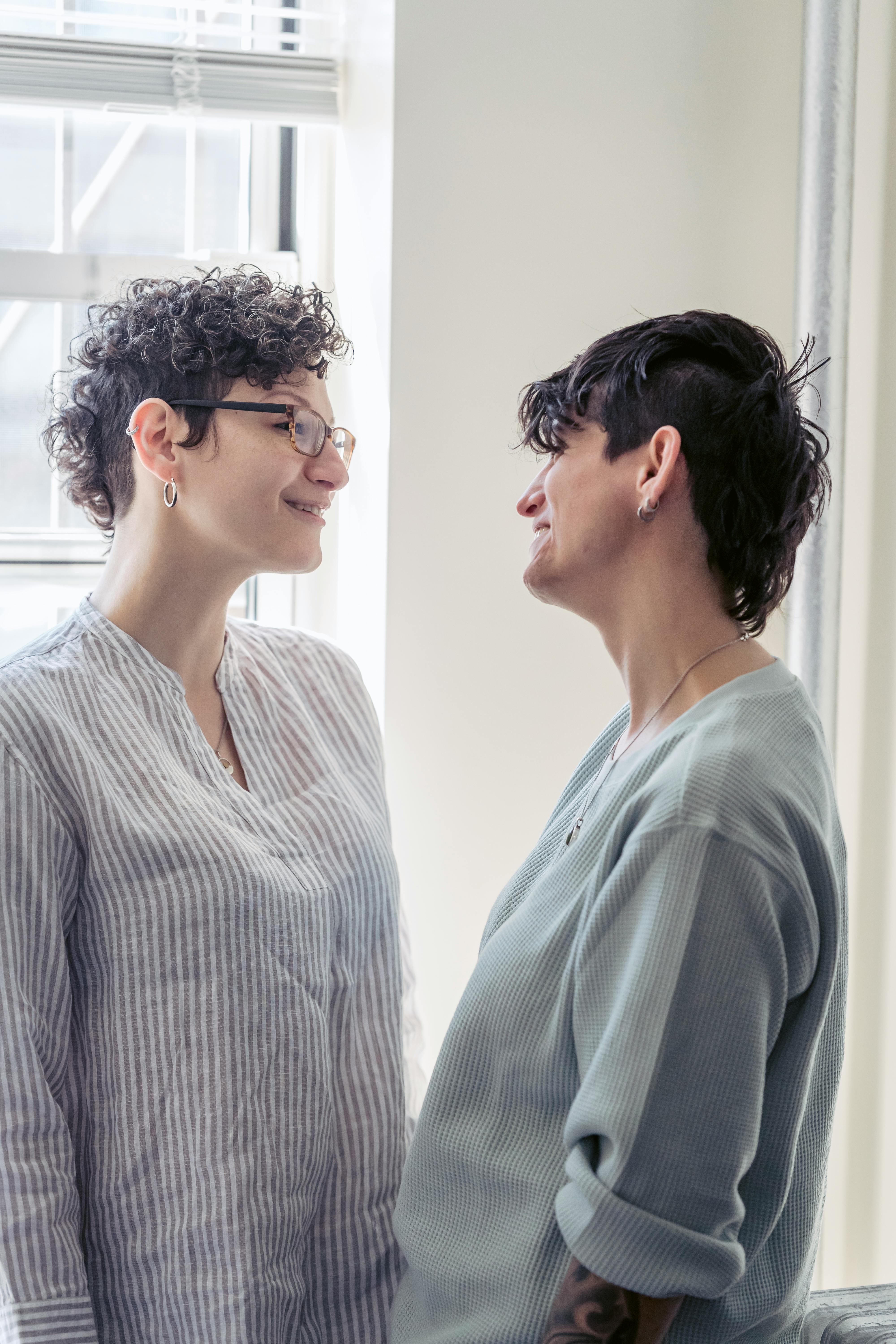 smiling lesbian couple talking in house room