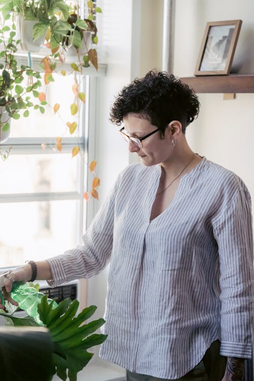 Woman in eyewear spraying plant at home