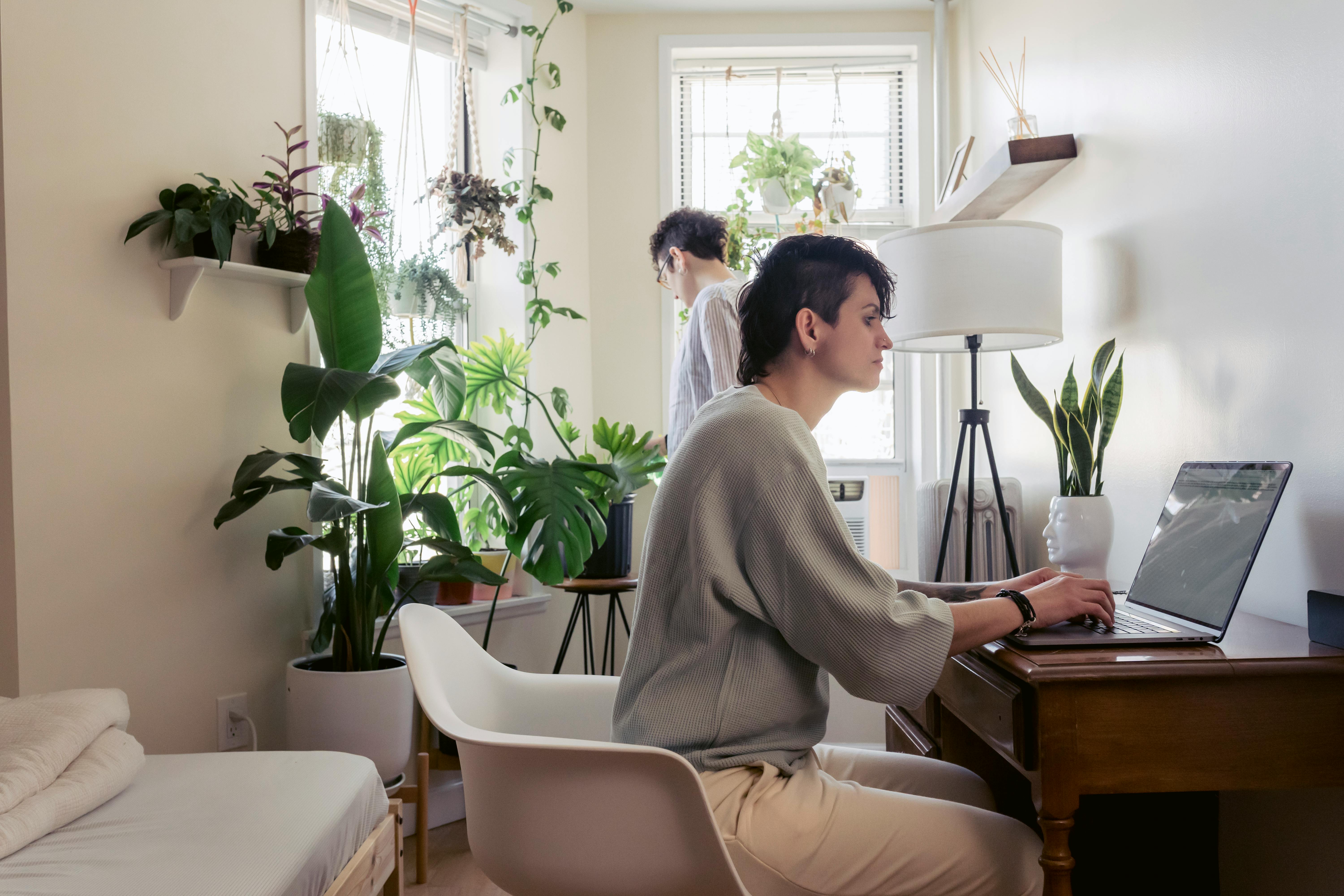 woman typing on laptop against girlfriend at home