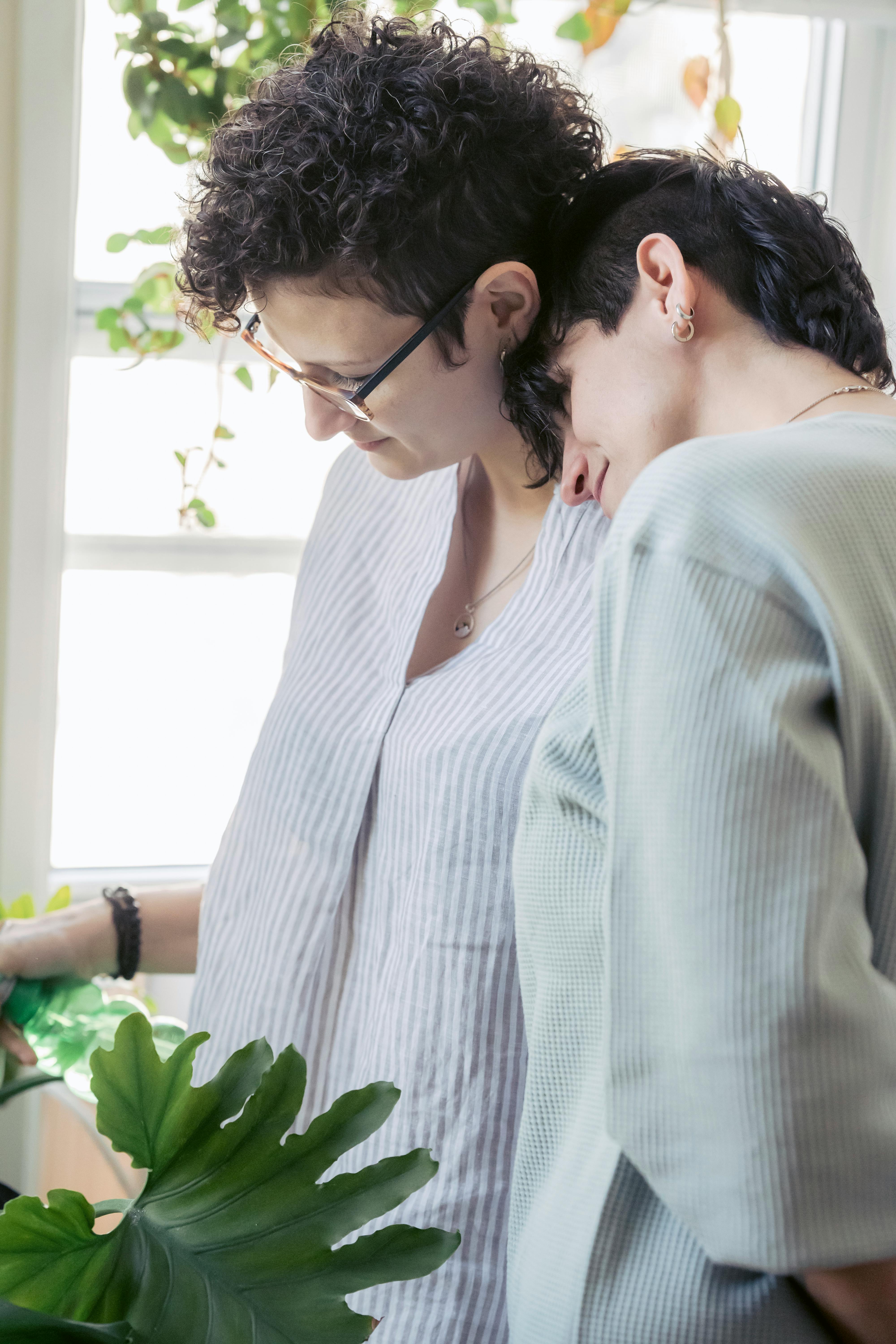 homosexual women interacting against plants at home