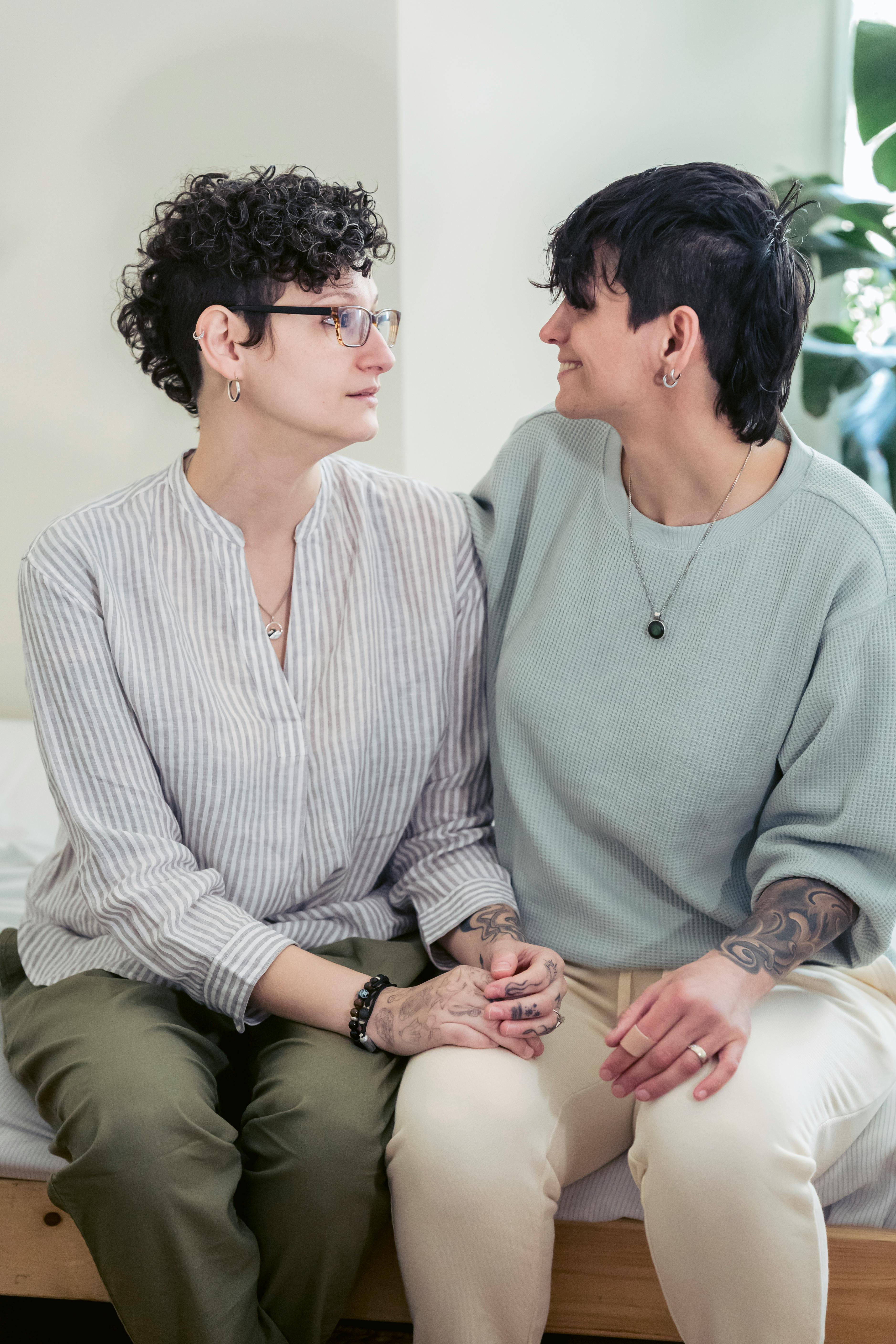 smiling homosexual women interacting on bed at home