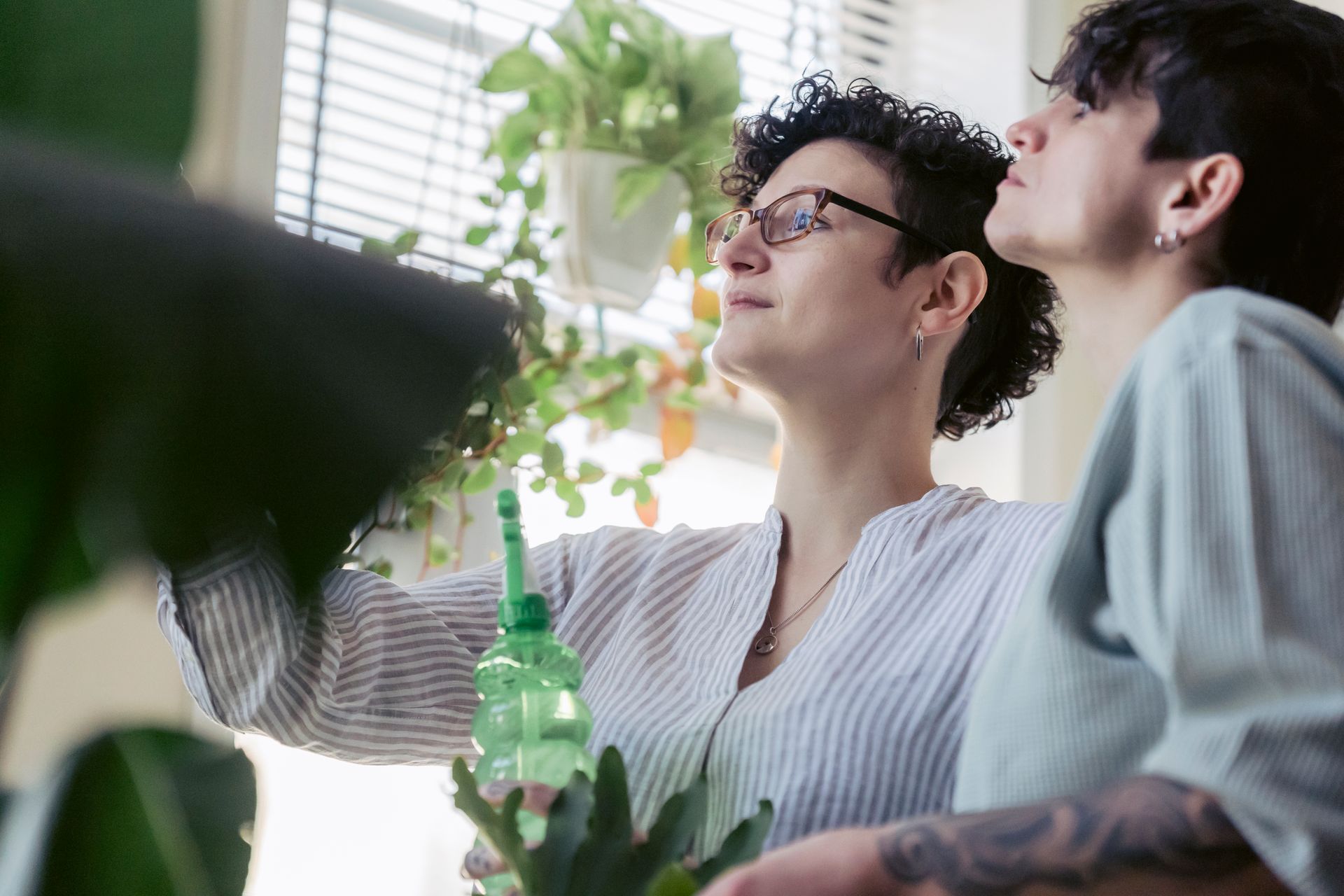 Two women engaging in indoor gardening, nurturing plants with care.