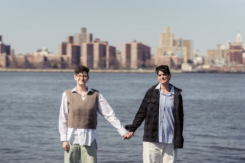 Content young lesbians holding hands near river in city