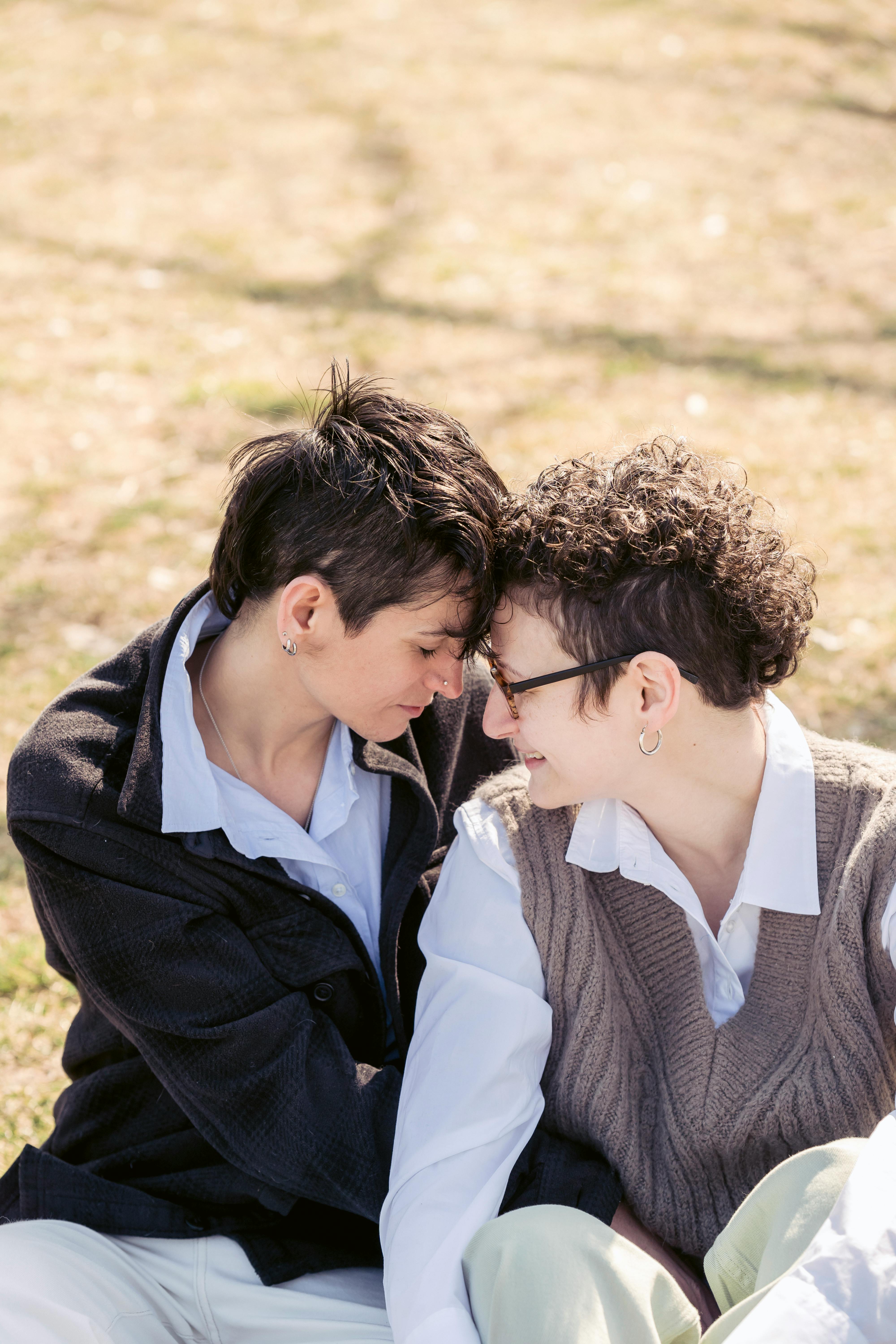 romantic young girlfriends touching foreheads while resting in park