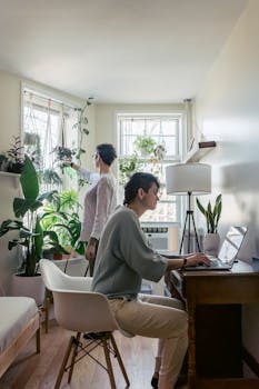 Two women working in a bright room filled with plants, creating a peaceful indoor environment.