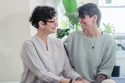 Free Woman in White and Gray Stipe Long Sleeve Shirt Sitting beside Woman in Teal Long Sleeve Shirt Smiling Stock Photo