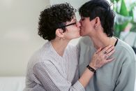 Woman in White and Gray Striped Shirt Kissing Woman in Teal Shirt
