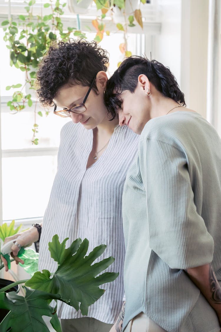 Couple Embracing While Watering Plants