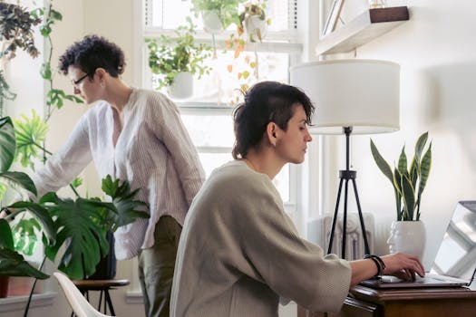 Lesbian couple working in a cozy home office with indoor plants, showcasing a modern lifestyle.