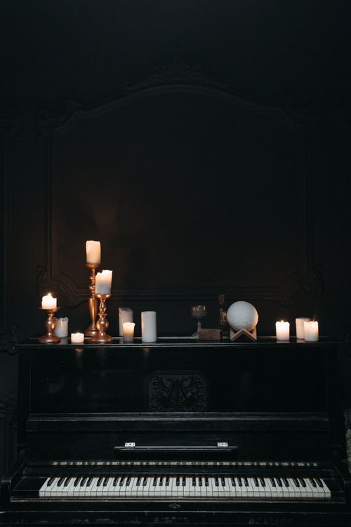 Free A dark, moodily-lit piano adorned with candles for a classic ambiance. Stock Photo