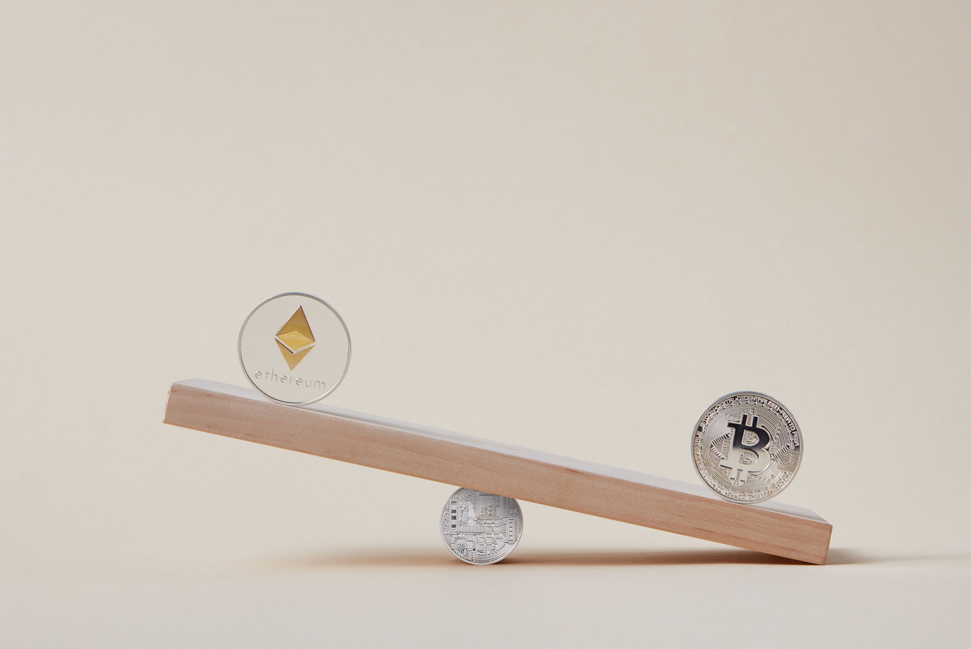 Minimalist image of Ethereum and Bitcoin coins balancing on a plank, symbolizing crypto market dynamics.