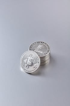 High-resolution image of stacked silver bitcoins and litecoins on a white background.