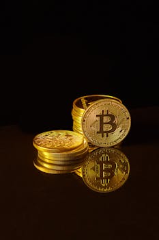 Golden bitcoins stacked on a reflective surface with a dark background.