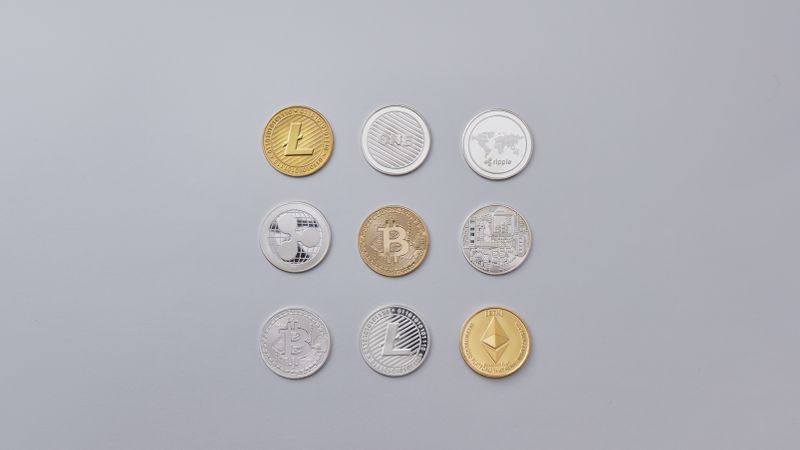 Image showcasing a selection of different cryptocurrency coins arranged on a neutral grey background.