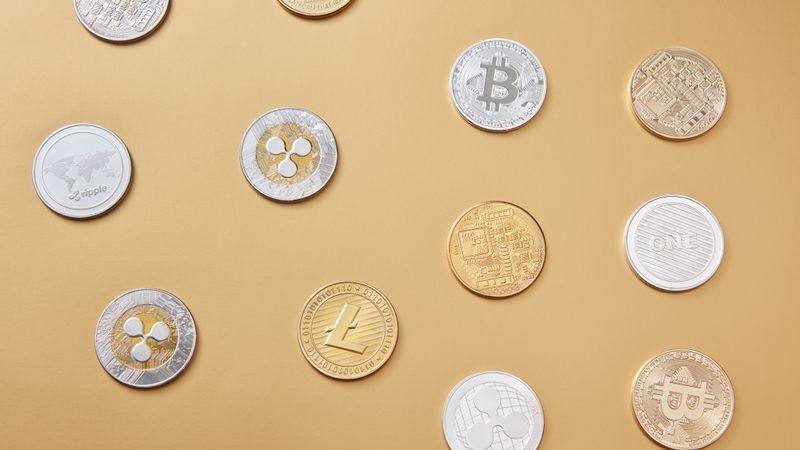 A flat lay of various cryptocurrency coins on a gold background, showcasing digital currency diversity.
