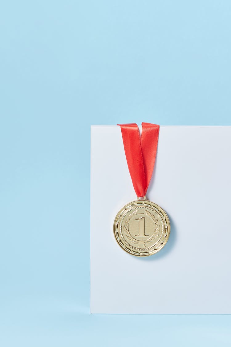 A Medal With Red Lanyard On White Paper