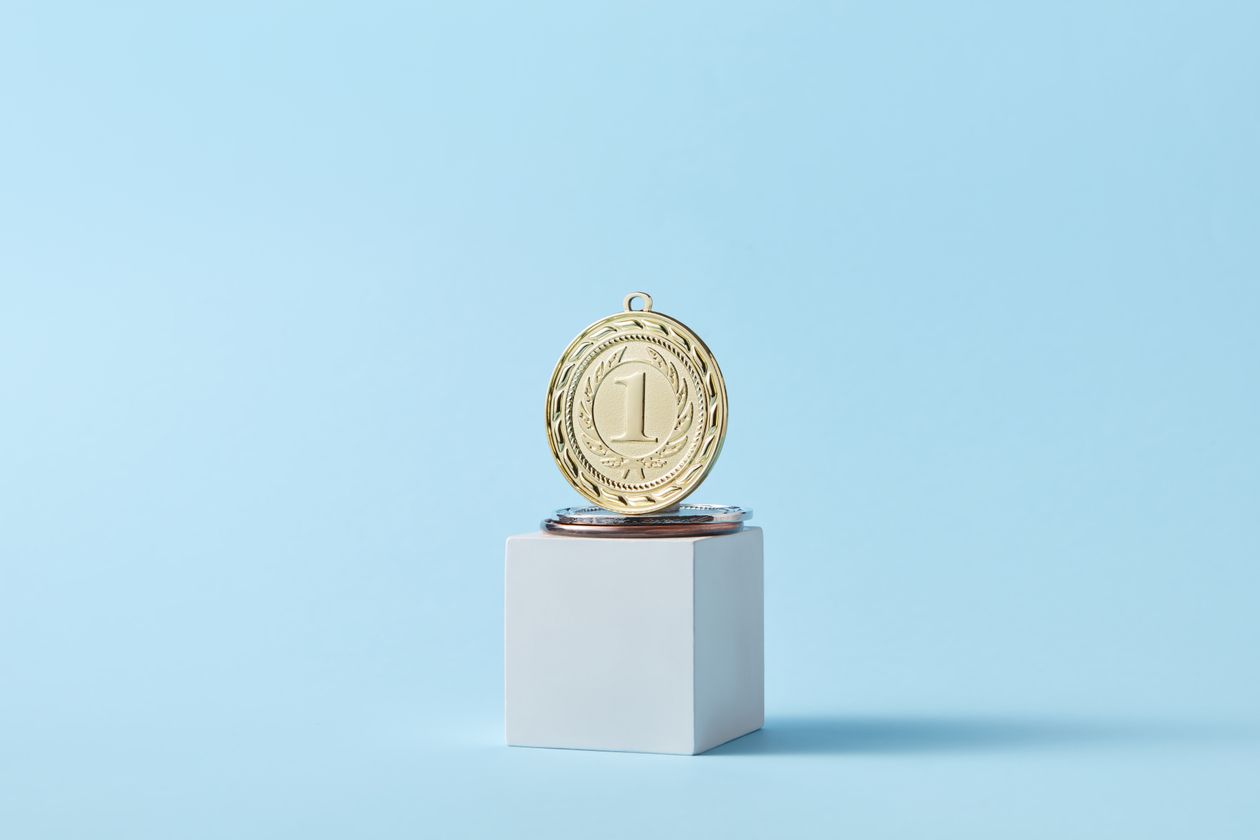 Gold medal on a podium against a baby blue background for the top referral marketing tool
