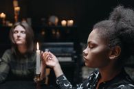 Two Women Holding Hands Near a Lighted Candle